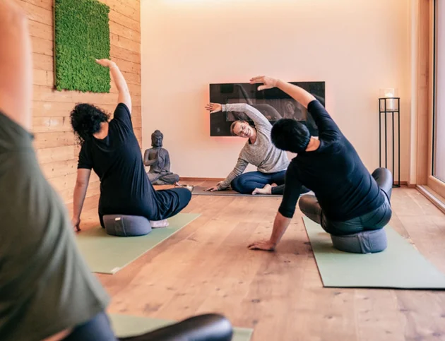 Yogastunde mit Teilnehmern, die seitliche Dehnübungen machen.