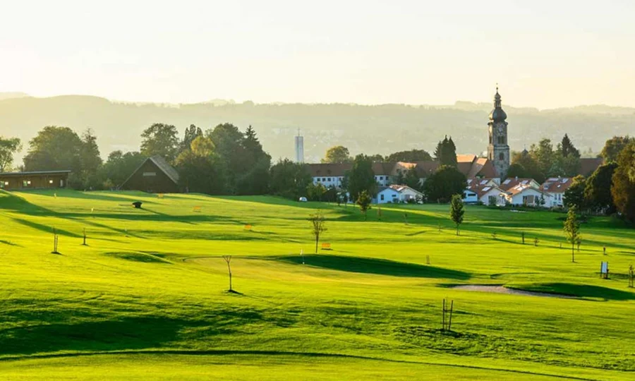 Sonniger Golfplatz mit Bunkern und langen Schatten im Morgenlicht.