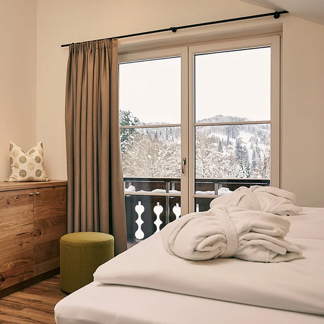 Gemütliches Doppelzimmer mit Balkonblick auf die verschneite Winterlandschaft im Hotel Birkenhof in Oberstaufen.
