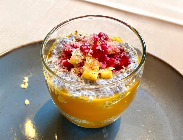 Dessert im Glas mit Mangopüree, Chia-Samen-Pudding, frischen Beeren und Kokosraspeln