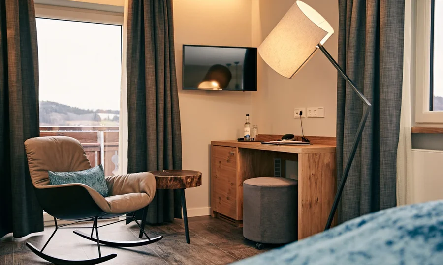 Moderne Zimmerecke mit Schaukelstuhl, Stehlampe, Schreibtisch und Blick auf den Balkon