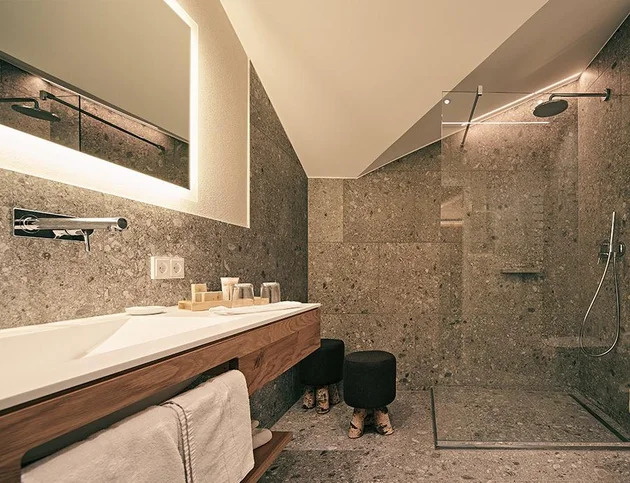 Schlafzimmer mit grünem Polsterbett, Schreibtisch und Zugang zum Balkon