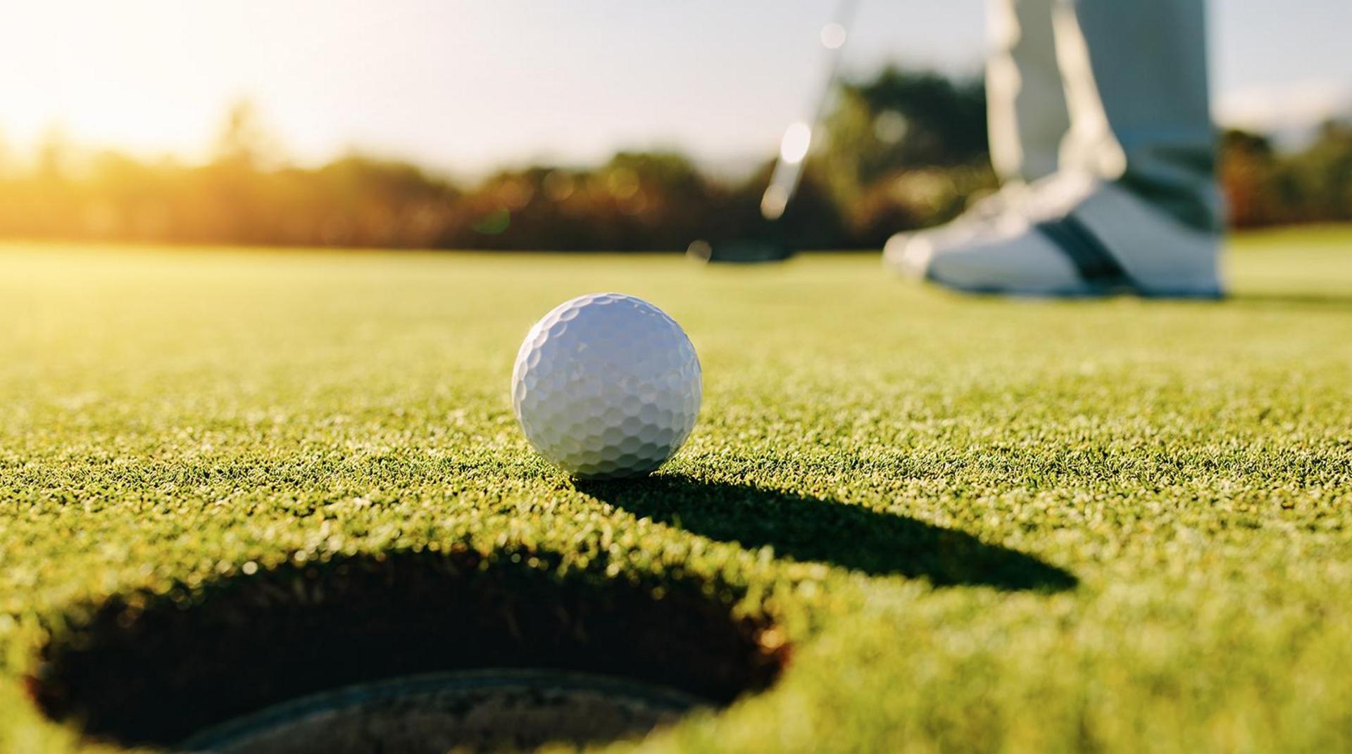 Golfball vor Golfloch Golfspieler auf Greenfee