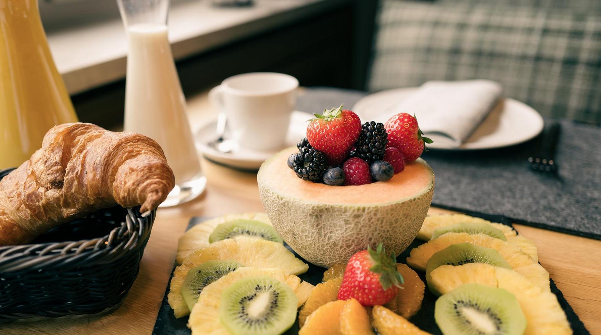 Frühstücksbuffett am Tisch mit Früchten Croissant Milch Orangensaft