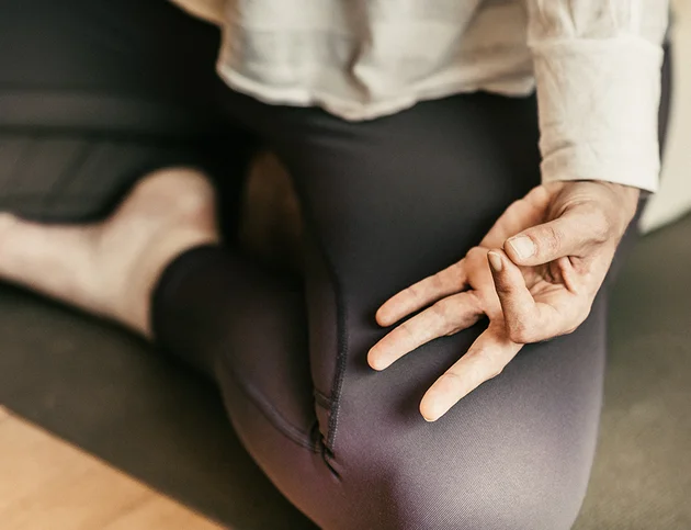 Person in Meditationshaltung mit Fokus auf Handgeste.