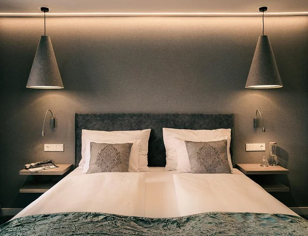 Doppelbett mit grauer Wand, modernen Lampen und stilvollem Ambiente