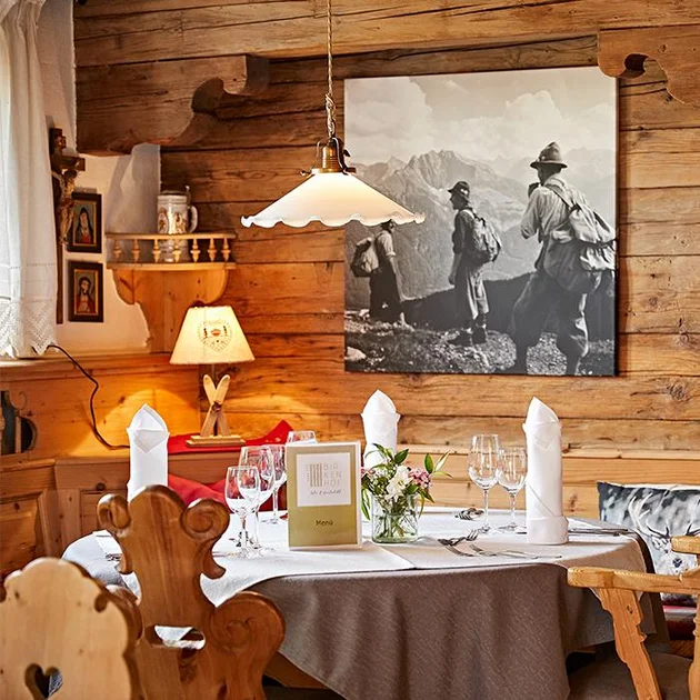 Die gemütliche Gaststube des Hotels Birkenhof mit einem elegant gedeckten Tisch für das Abendessen, dekoriert mit Kerzen und Geschirr in einer warmen Atmosphäre