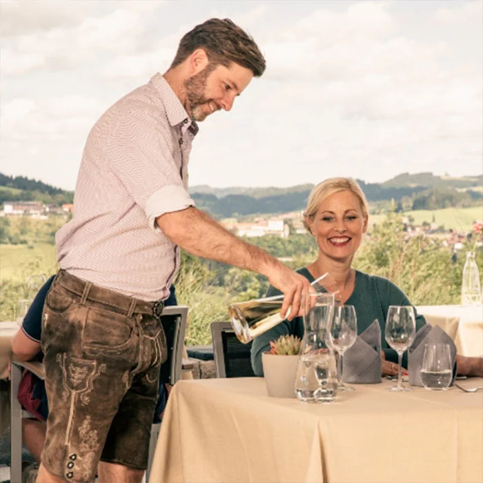 Kellner serviert Wein einer Frau auf der Hotelterrasse.