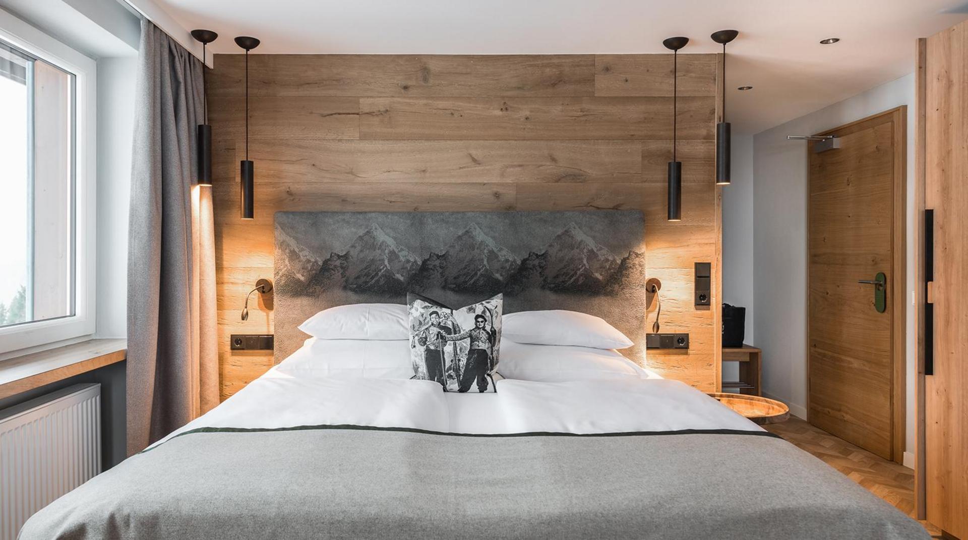 Modernes Hotelzimmer mit Doppelbett, Holzverkleidung und indirekter Beleuchtung.