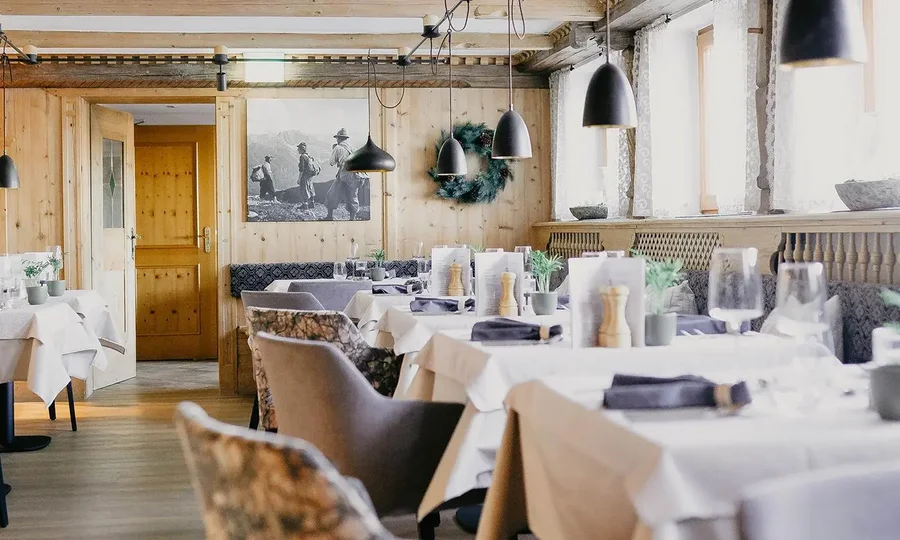 Restaurantstube mit Holzwänden und gedeckten Tischen, gemütliche Atmosphäre und rustikales Design