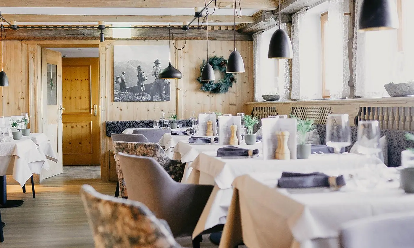 Restaurantstube mit Holzwänden und gedeckten Tischen, gemütliche Atmosphäre und rustikales Design