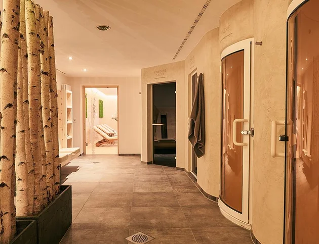 Wellnessbereich im Hotel Birkenhof mit modernen Saunakabinen, Ruhebereich im Hintergrund und dekorativen Birkenstämmen.