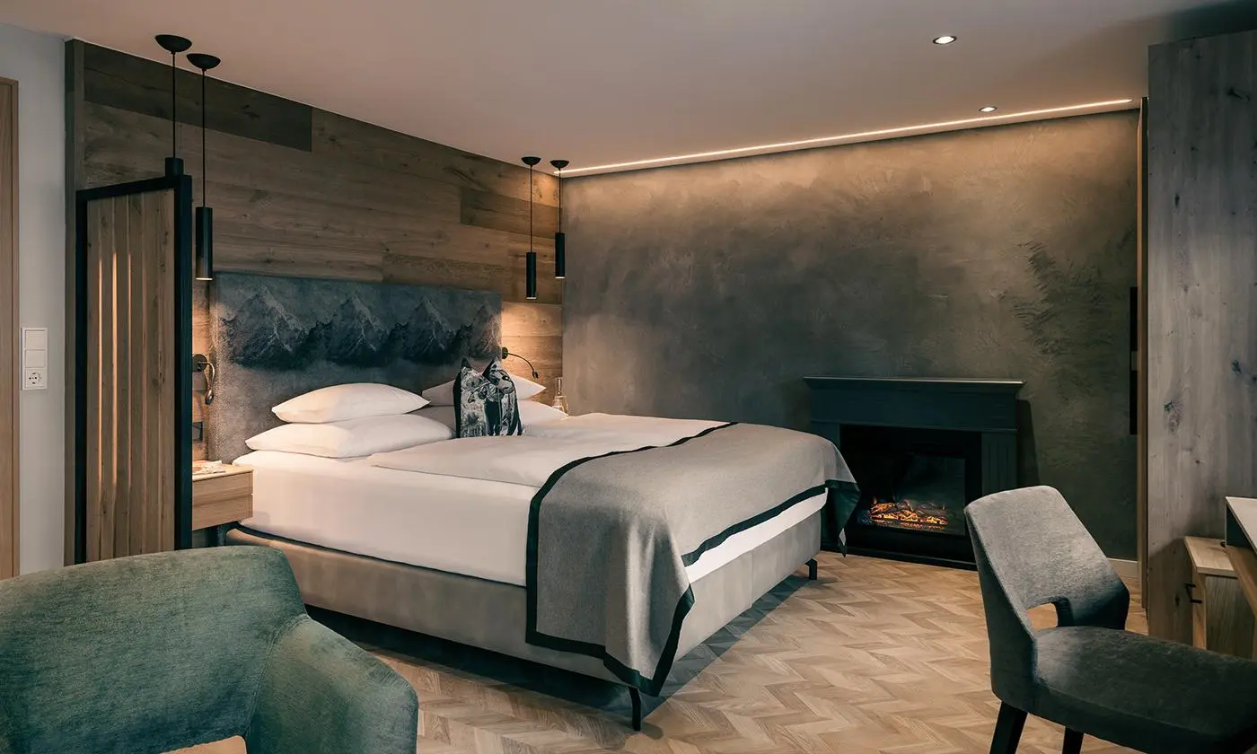 Modernes Hotelzimmer mit großem Bett, grauen Akzenten, Kamin und edlem Design