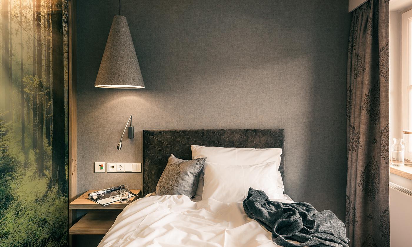 Kleines stilvolles Einzelzimmer mit grauer Wand, Waldmotiv und modernem Lichtdesign