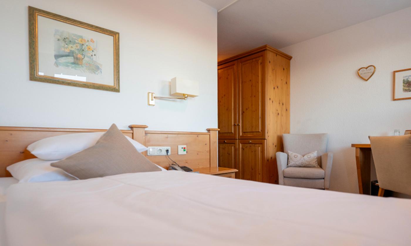 Gemütliches Hotelzimmer mit Holzdetails, Doppelbett und Sitzbereich im Landhausstil